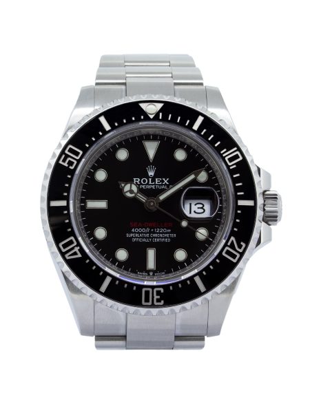 Rolex Sea-Dweller 126600 wristwatch worn on a man's wrist while driving a luxury sports car. The 43mm Oystersteel watch features a black dial, black Cerachrom bezel, luminous hour markers, and a date display with Cyclops lens. Photographed from the driver's perspective, the watch is positioned above the steering wheel with the road softly blurred in the background, creating a sophisticated automotive lifestyle scene.