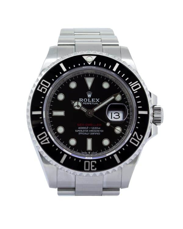 Rolex Sea-Dweller 126600 wristwatch worn on a man's wrist while driving a luxury sports car. The 43mm Oystersteel watch features a black dial, black Cerachrom bezel, luminous hour markers, and a date display with Cyclops lens. Photographed from the driver's perspective, the watch is positioned above the steering wheel with the road softly blurred in the background, creating a sophisticated automotive lifestyle scene.