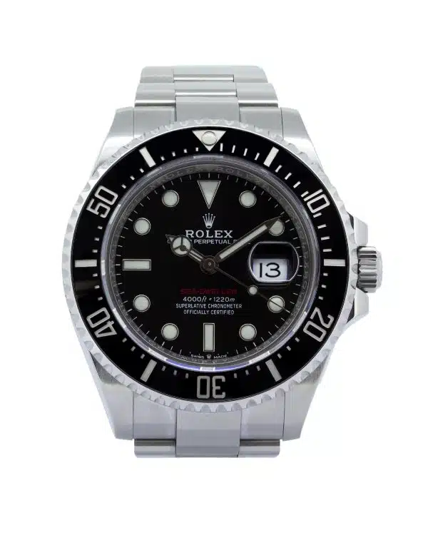 Rolex Sea-Dweller 126600 wristwatch worn on a man's wrist while driving a luxury sports car. The 43mm Oystersteel watch features a black dial, black Cerachrom bezel, luminous hour markers, and a date display with Cyclops lens. Photographed from the driver's perspective, the watch is positioned above the steering wheel with the road softly blurred in the background, creating a sophisticated automotive lifestyle scene.